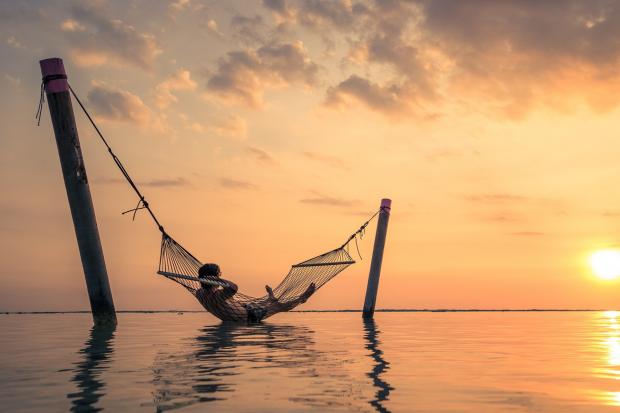 Irvine Times: A man relaxing over the water in a hammock. Credit: Canva