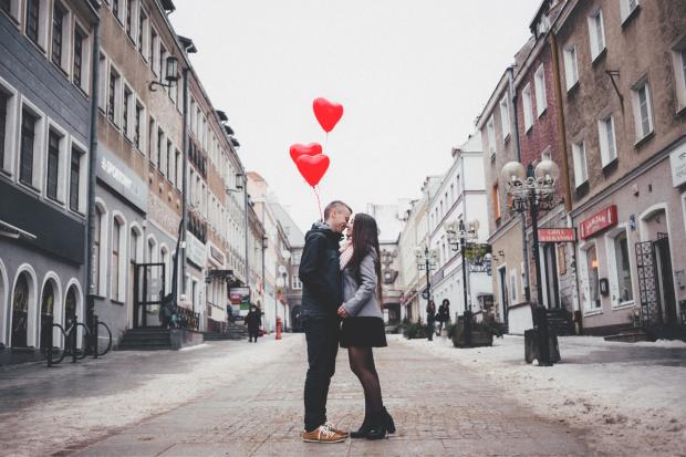 Irvine Times: A couple embracing on the street in front of heart balloons. Credit: Canva