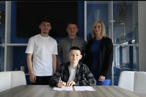 Harvey poses with his proud family as he signs his deal. Pic credit: Harvey Gilmour